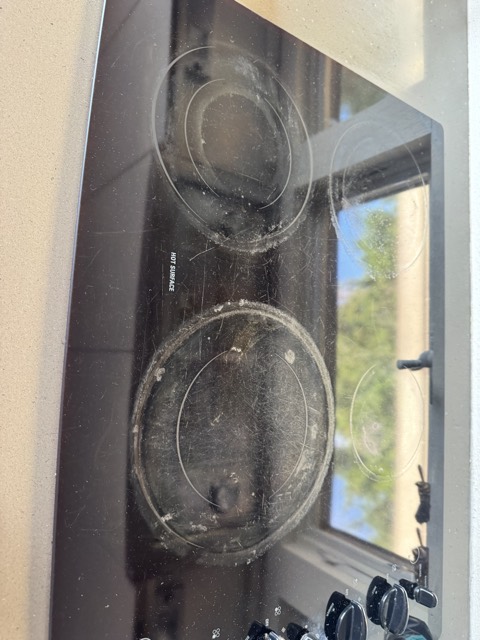 Glass cooktop with built-up grease before deep cleaning